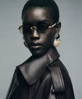 Model wearing ASAP Rocky RB3928 Slim Rimless Metal Rectangular Sunglasses in Gold and Dark Green 54mm Frames with a leather coat