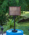 Outdoor Table Lamp With Tropical Bamboo Shade In Oil Rubbed Bronze Highlight Finish Casual Style Patio Light For Deck Or Porch 29 Inch Tall With 14 Inch Shade Diameter On Off Socket Switch shown on a patio table.