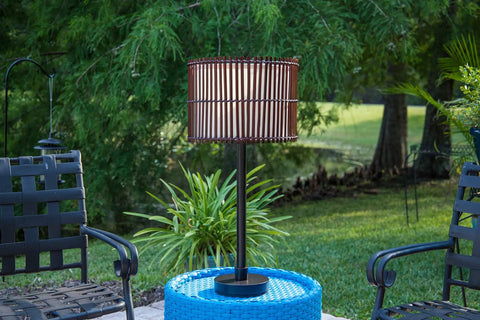 Outdoor Table Lamp With Tropical Bamboo Shade In Oil Rubbed Bronze Highlight Finish Casual Style Patio Light For Deck Or Porch 29 Inch Tall With 14 Inch Shade Diameter On Off Socket Switch shown on a patio table.