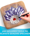 Person using a tool to excavate crystals from Gemstone Dig Kit For Kids With 15 Real Gemstones And Crystals Hands On Science Toy For Boys And Girls Gem Mining Kit Educational Rock Collection Gift For Curious Kids And Nature Lovers.