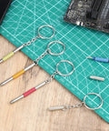 Handy 3-In-1 Eyeglass Repair Kit with keychain screwdrivers in five colors on a green cutting mat for electronics and glasses repair.