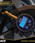 Front view of JACO Elite digital tire pressure gauge with brass air chuck and blue LCD display, held by a gloved hand.