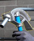 Heavy Duty 3/4 Inch Emt Electrical Conduit Bender By Ideal held in hand with blue handle, showing heat treated bending head, on gray wall.