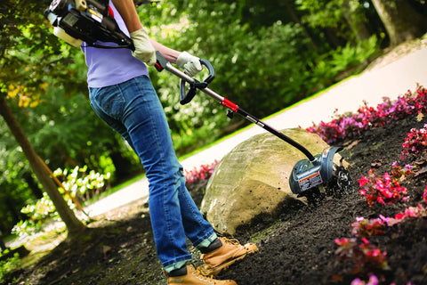 Person using Garden Tiller Cultivator Attachment For Gas Powered Multi-Use Outdoor Equipment in flower bed