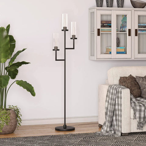 Three Light Torchiere Floor Lamp with Glass Shades in Blackened Bronze and Clear Finish beside a sofa in a living room setting