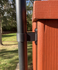 Side view of black outdoor torch bracket mounted on a fence, supports 1-1/4-inch poles; Deck Or Fence Mount For Tiki Torches And 1-1/4-Inch Poles Fits Solar Lights Black Outdoor Torch Bracket With Ground Clearance And Vertical Mount Keeps Deck Surfaces Clutter-Free.