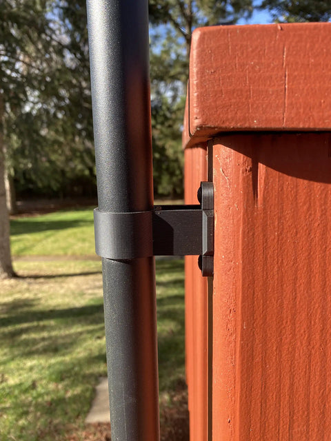 Side view of black outdoor torch bracket mounted on a fence, supports 1-1/4-inch poles; Deck Or Fence Mount For Tiki Torches And 1-1/4-Inch Poles Fits Solar Lights Black Outdoor Torch Bracket With Ground Clearance And Vertical Mount Keeps Deck Surfaces Clutter-Free.