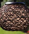 Close-up of woven rattan shade on Castillo Outdoor Floor Lamp With Oil Rubbed Bronze Highlight Finish in backyard.