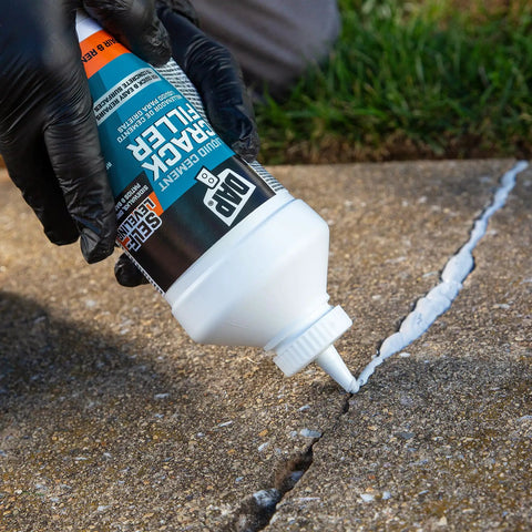 Easy To Use Liquid Cement Crack Filler For Concrete Patch Up Cracks Fast Self Leveling Interior And Exterior Repair Dries Gray To Match Existing Concrete 32 Oz being poured into sidewalk crack