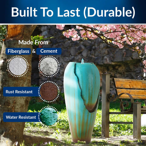 Outdoor Antique Jar Water Fountain With LED Lights 33 Inch Turquoise Cascading Water Feature For Garden Patio And Yard Decor Cool Night Glow And Tranquil Backyard Vibe next to park bench with blooming tree in background.