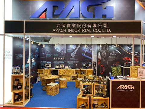 Trade show booth with air tools displayed by Apach Industrial Co., blue carpet, wooden shelves, industrial lighting
