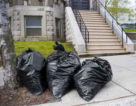 Heavy Duty 55 Gallon Contractor Trash Bags 3 Mil Thick Black Liners With Ties outside a building staircase.