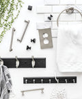 Black Wall Mount Key Rack With 7 Hooks For Hallway And Entry next to towel ring and green leaves against white tile wall.