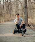 Person seated on Beast Buggy Go Kart Attachment For 10 Inch Hoverboards With Hand Operated Rear Wheel Control on a path.