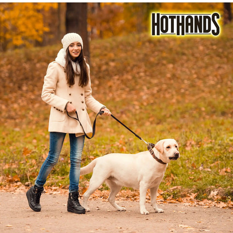 Woman walking a dog in autumn with HotHands logo at top right