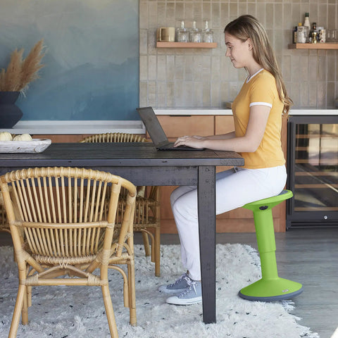 Woman using SitWell Wobble Stool With Adjustable Height For Active Seating In Classrooms And Libraries Grassy Green in kitchen