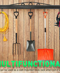 Wall-mounted tool rack holding garden tools, extension cord, and saw against wooden background.