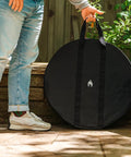 Person resting Medium Heat Deflector Carry Bag For Bonfire Accessories against stone wall outdoors.