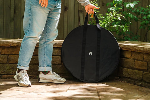 Person resting Medium Heat Deflector Carry Bag For Bonfire Accessories against stone wall outdoors.