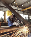 Worker using Flat Head Angle Grinder Ultra Compact For Tight Spaces And 43 Degree Angles on metal beam, sparks flying