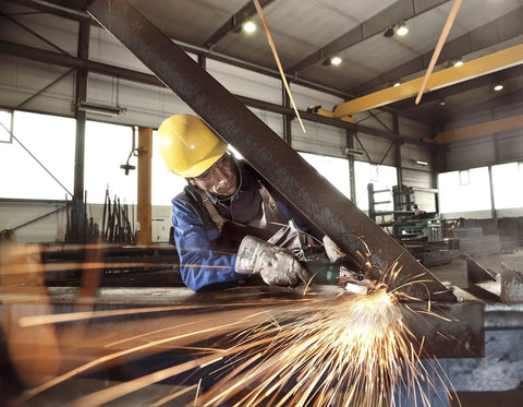 Worker using Flat Head Angle Grinder Ultra Compact For Tight Spaces And 43 Degree Angles on metal beam, sparks flying