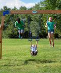 Children playing on the Beachfront Cedar Wood Swing Set With Wave Slide Elevated Deck Canopy Monkey Bars Rock Wall Ladder Shaded Picnic Area Snack Bar Window Belt Swings Trapeze Sandbox Playset For Kids in a backyard.