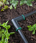 Close-up of Raindrip 1/2-in compression elbows on black irrigation tubing with green rings