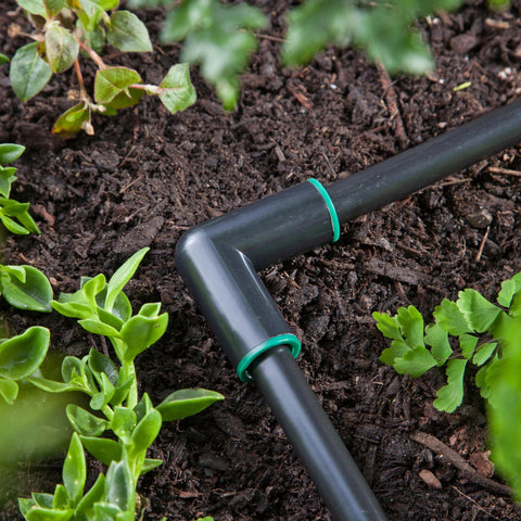 Close-up of Raindrip 1/2-in compression elbows on black irrigation tubing with green rings