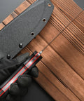 Rugged AUS 10 Fixed Blade Knife With Carbon Fiber Handle shown with sheath on wooden background