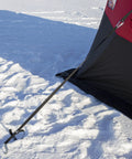 Heavy Duty Pop Up Insulated Ice Fishing Shelter With Knockout Spacious Fishin Spot For Five To Seven Crews Quick Roll Setup Trip Proof Door Wide Flared Bottom Red Black 94 Square Feet securing strap on snow ground.