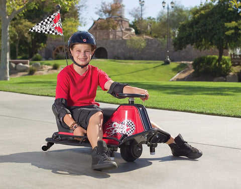 Child riding Crazy Cart Sport 24V Electric Drifting Go Kart with Variable Speed Pedal, outdoor setting, helmet on for safety.