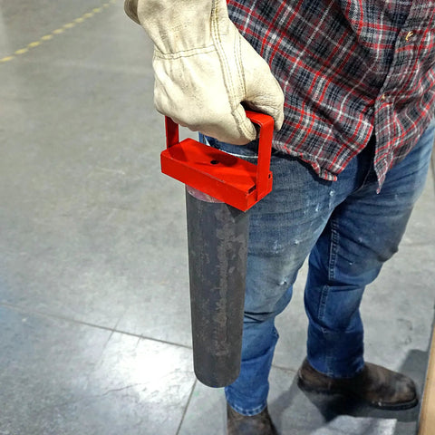 Person using Red 150 Lb Pull Heavy Duty Handle Magnet for tools to lift metal rod on workshop floor.