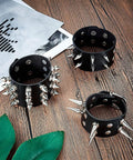 Six Piece Punk Leather Bracelet Set Featuring Hardcore Spikes Mixed Metal Studs Black Cuff Bands arranged on wood with greenery.