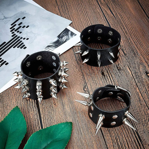 Six Piece Punk Leather Bracelet Set Featuring Hardcore Spikes Mixed Metal Studs Black Cuff Bands arranged on wood with greenery.