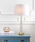 Crystal LED Table Lamp In Clear And Brass Gold Finish, 29.5 Inch Two Light Contemporary Glam Bedside Lamp With White Linen Drum Shade, Pull Chain, Energy Saving Bulbs Included, Perfect Living Room Accent on a blue table.