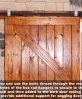 4 Pack Box Rail Hanger Brackets With Bolts For Exterior Barn Door Hardware installed on wooden barn door against stone wall.