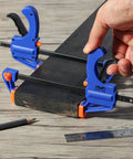 Woodworking Bar Clamps 4 Inch Set of 2 Quick Release One Handed Clamps With Hardened Steel Bar And Soft PVC Pads For Small DIY Projects 65 Lb Clamping Force Blue, holding a wooden plank with pencil and ruler nearby.