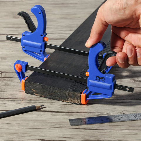 Woodworking Bar Clamps 4 Inch Set of 2 Quick Release One Handed Clamps With Hardened Steel Bar And Soft PVC Pads For Small DIY Projects 65 Lb Clamping Force Blue, holding a wooden plank with pencil and ruler nearby.