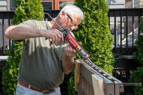 Man applying Heavy Duty Construction Adhesive For Wood Concrete Stone And More Premium Max Strength Bond That Stays 100 Percent Solid After Curing In A 9 Oz Cartridge 1 Pack on outdoor structure