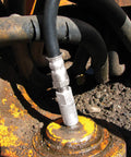 Silver metal grease-fitting adapter on a black hose attached to a rusted orange machinery joint