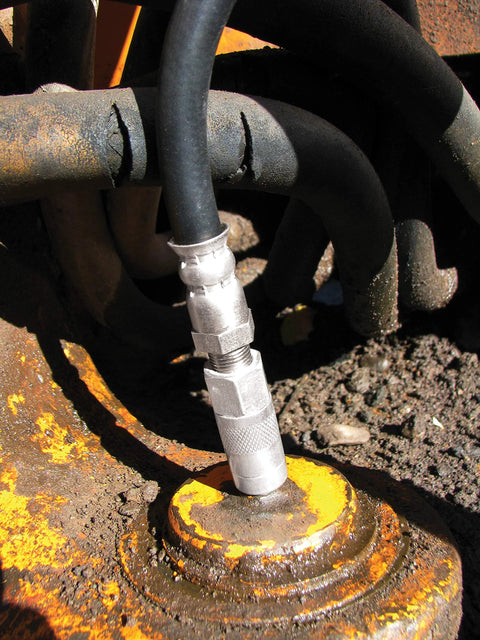 Silver metal grease-fitting adapter on a black hose attached to a rusted orange machinery joint