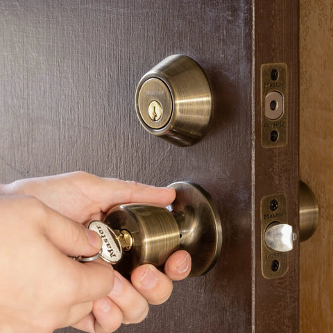 Person using key in Keyed Entry Door Lock With Single Cylinder Deadbolt And Tulip Style Knob In Antique Brass Finish, Model TUCO0605 Combo