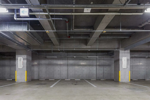 15 Pack White Surface Mount Fire Extinguisher Cabinet With Breaker Bar for 5 Lb units mounted in a concrete parking garage.