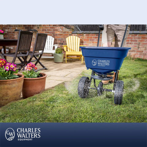 Heavy Duty Homeowner Broadcast Spreader With 65Lb Capacity And Powder Coated Steel Frame For Spreading Grass Seed Fertilizer And Ice Melt On Lawns And Driveways With Smooth Roll On Two 10 Inch Pneumatic Tires being used on a lawn