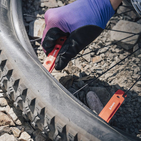 Using Bike Tire Levers With Chain Master Link Pliers Kit for tire repair on gravel trail, orange nylon levers visible