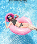 Woman in sunglasses and pink hat floating in pool on a pink inflatable ring