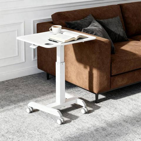 Portable Laptop Cart On Wheels With Adjustable Height Sit Stand Desk And A 28.5 By 22 Inch Tabletop In White next to a sofa