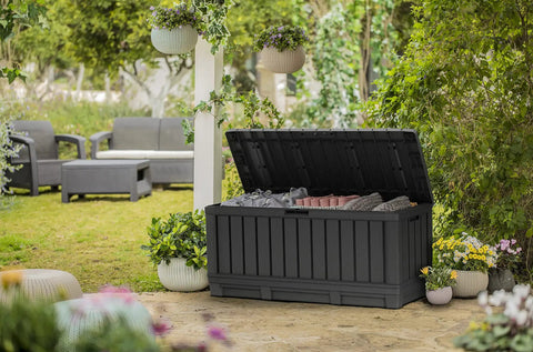 92 Gallon Resin Deck Box In Dark Gray For Outdoor Storage Keep Patio Cushions And Throw Pillows Garden Tools Pool Floats Neat And Ready To Grab On The Patio Or In The Garage, open with pillows inside, surrounded by garden
