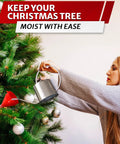 Person watering a Christmas tree using a red funnel and metal watering can