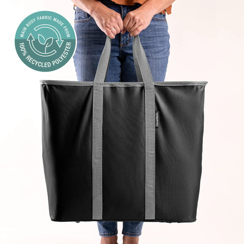 Person holding a black laundry tote with gray handles, highlighting its 100% recycled polyester fabric.